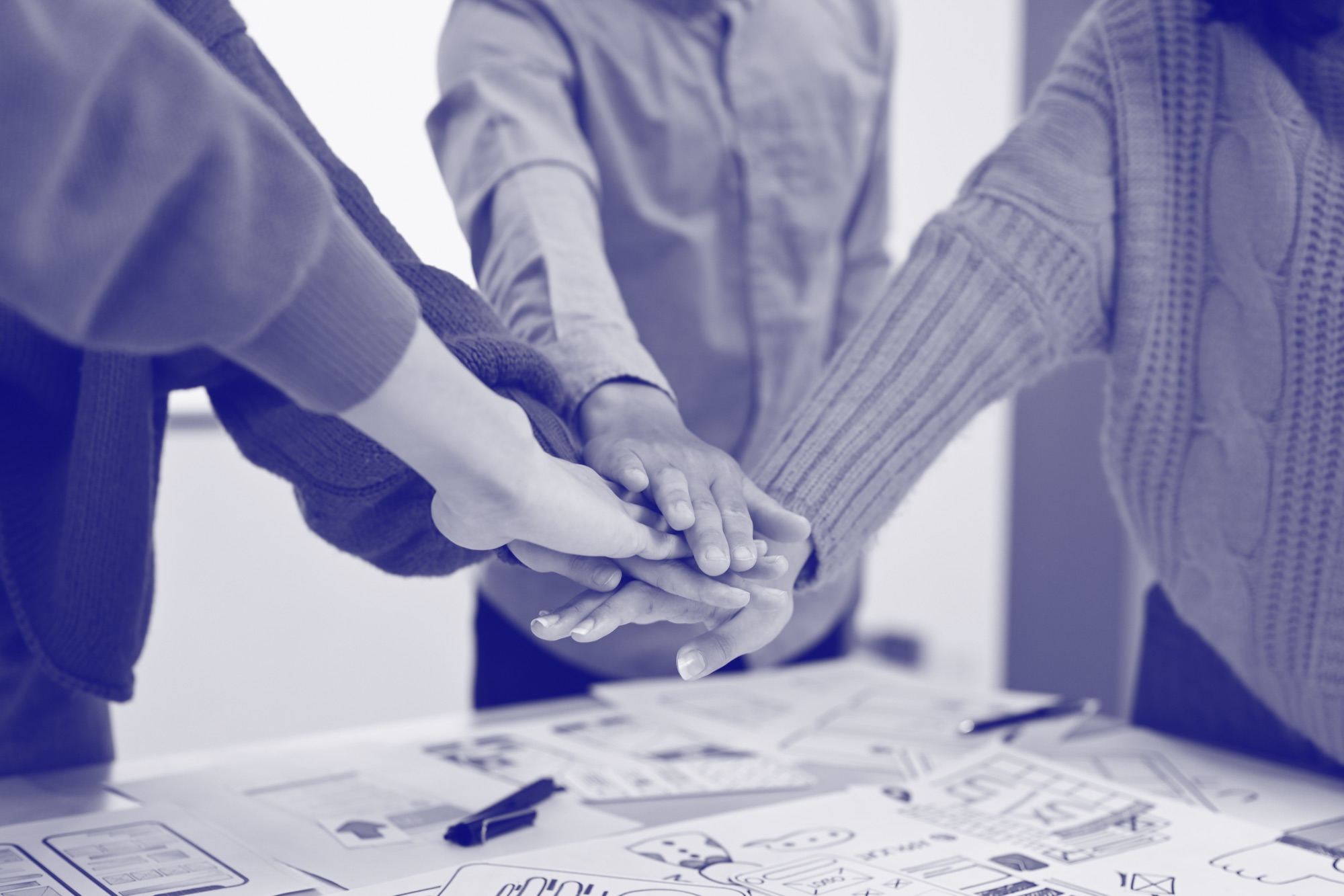 Manos de un equipo de trabajo unidas sobre una mesa